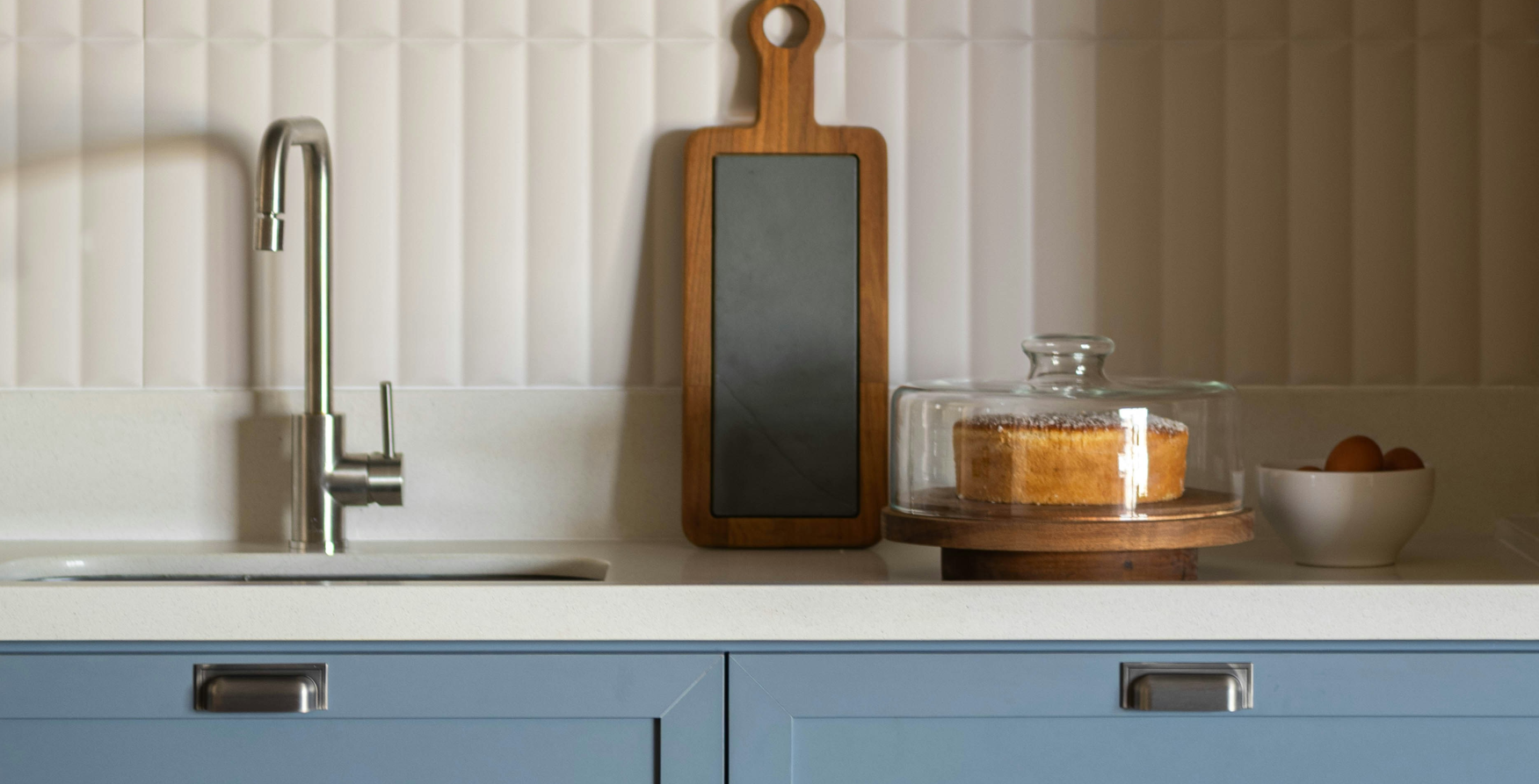 Blue kitchen cabinets paired with creamy off-white surface and splashback